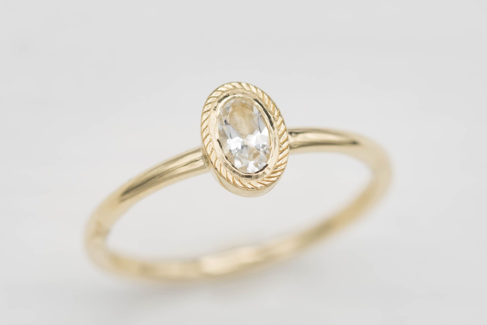 Oval white topaz in a delicate yellow gold bezel setting